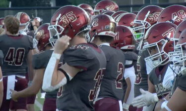 A large group of Rigby football players stand on the sidelines.